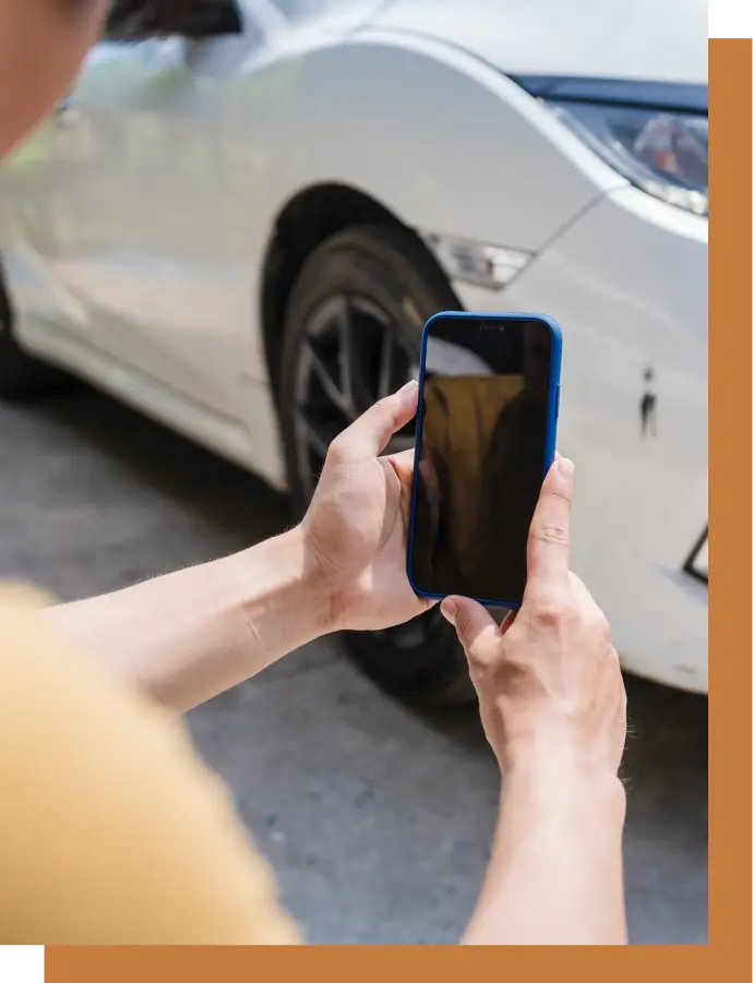 A driver takes a picture of damage after a car accident to give to her car accident attorney.